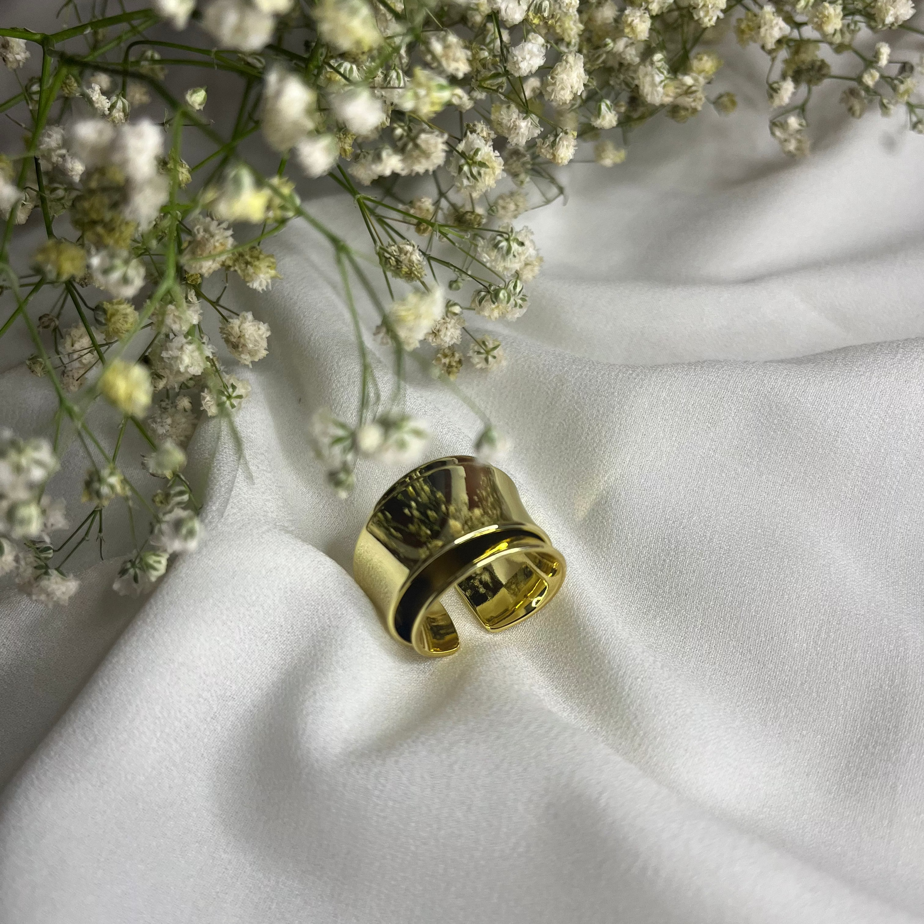 Gold ring on a white fabric background with small white flowers