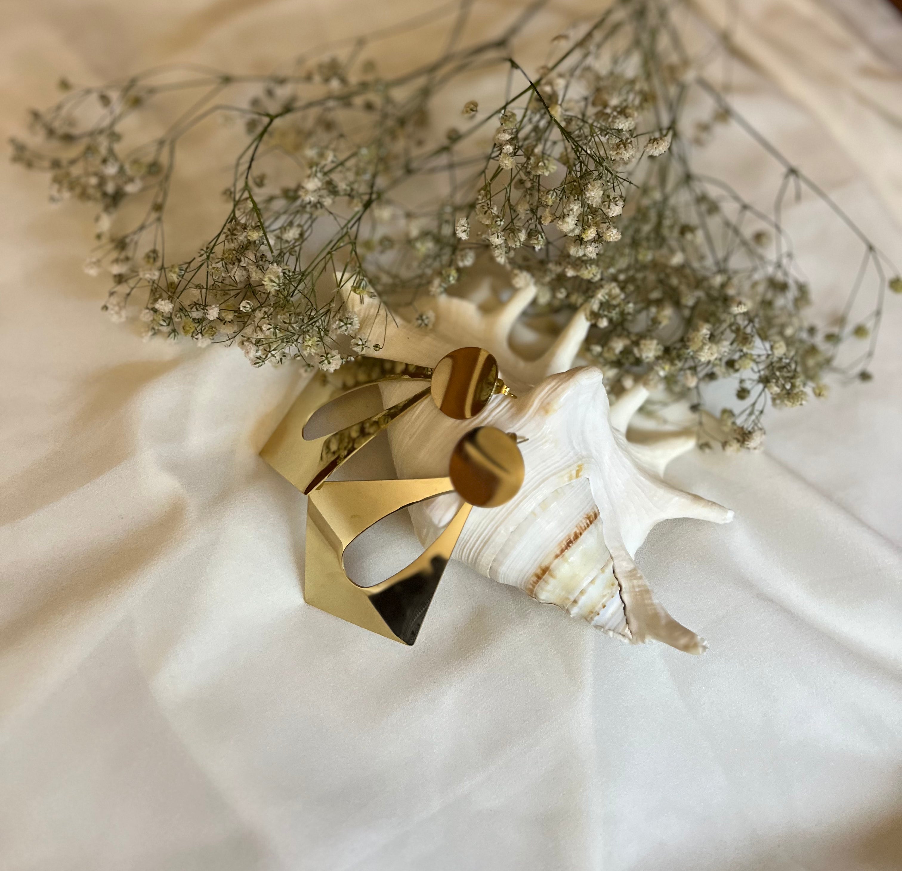 Gold ring on a white surface with dried flowers in the background