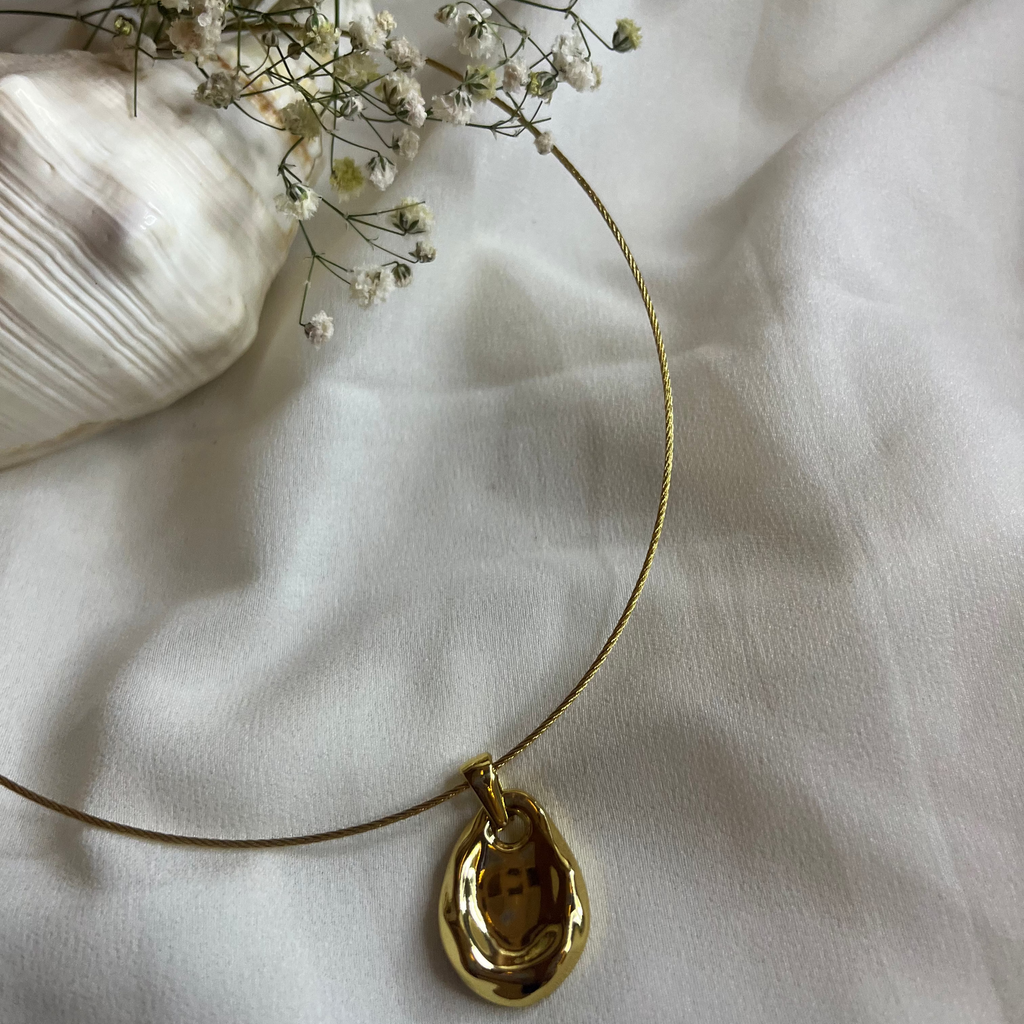 Gold necklace with a pendant on a white fabric background