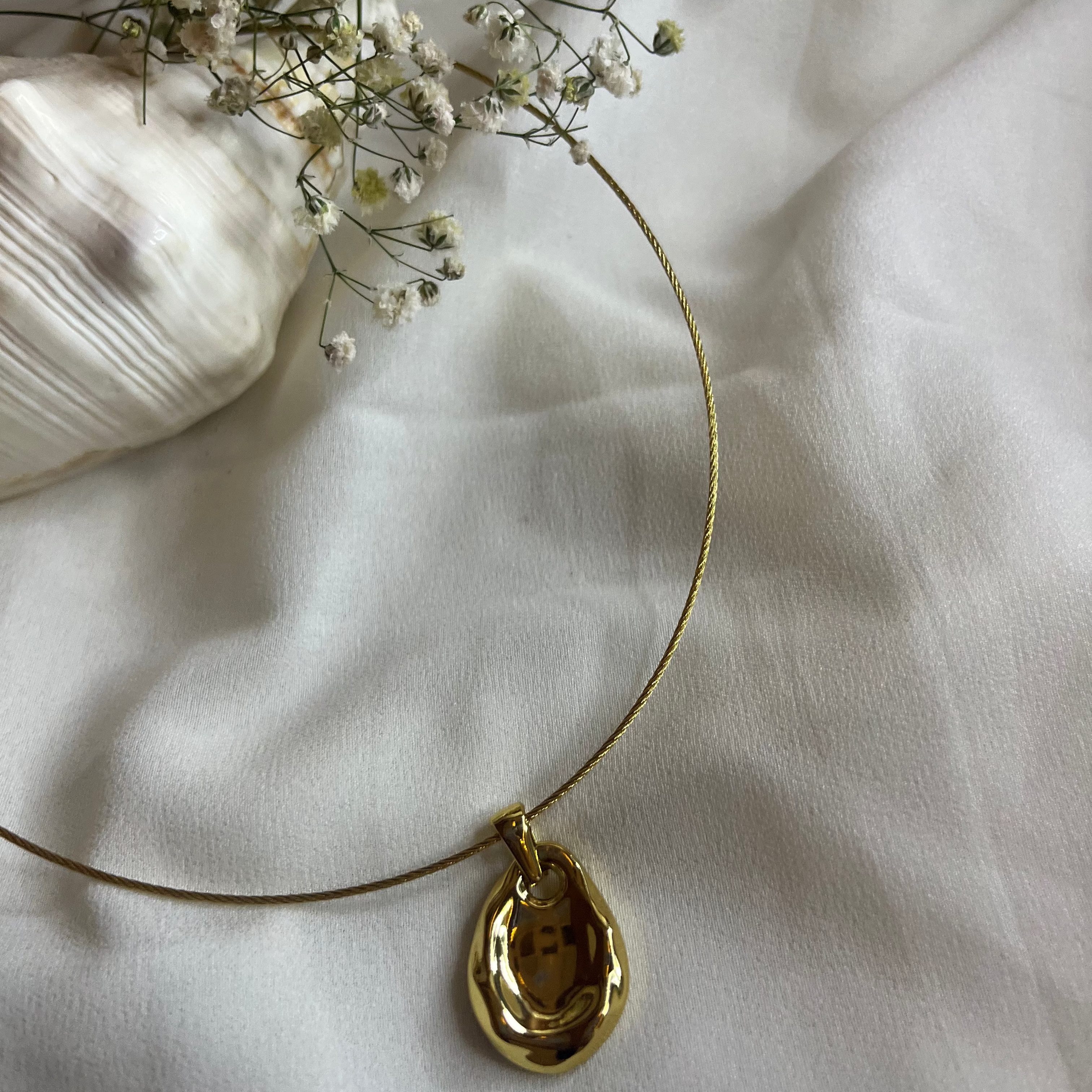 Gold necklace with a pendant on a white fabric background
